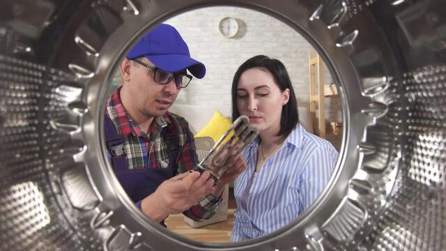 Repairman and housewive next to the washing machine discuss the breakdown