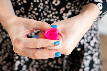 Woman folding menstrual cup in hands close up