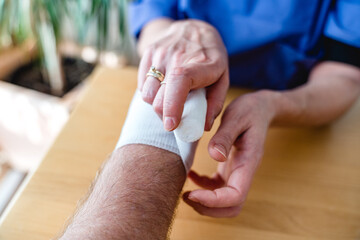 Close-up of female nurse bandaging a hand or arm home care