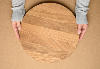woman holding empty round wooden pizza board in hand