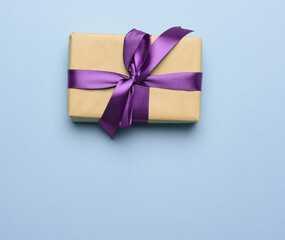 box wrapped in brown paper and tied with a purple silk ribbon