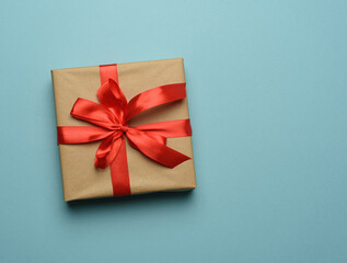 box wrapped in brown paper and tied with a red silk ribbon with a bow