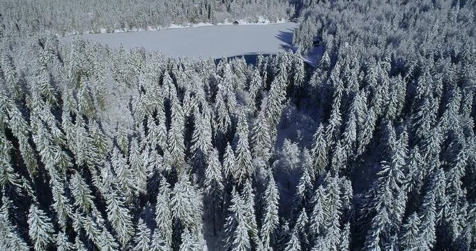 Aerial drone flying over frozen Laghi di Fusine lake in Italy. Inferior lower Fusine lake in winter season. Overhead view of pristine beautiful landscape, idyllic nature. Forward moving, ascending
