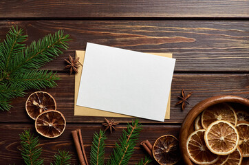 Christmas card mockup with dry oranges, fir tree branches, christmas spices and decorations on wooden background