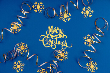 Holiday background with Merry Christmas wording, golden snowflakes, and ribbons on classic blue. Holiday celebration card concept