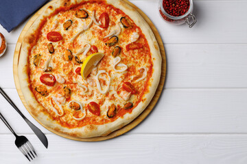 Seafood pizza on board on white wooden table