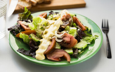 vegetable salad of greens, tomatoes and cucumbers on a green plate