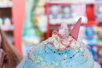 Child eating sweets and candy on a huge cotton candy floss with ice cream and dessert sauce