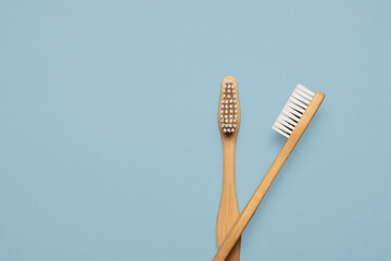 Two wooden natural bamboo toothbrushes flat lay on a blue background with copy space and room for text with a right side composition