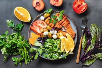 Top view healthy balanced lunch with grilled red fish fillet salmon with various vegetables, cheese and fruits on dark background