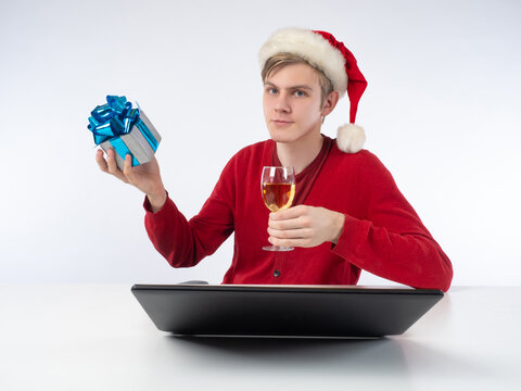 Remote Christmas Congratulations. Young Man Wears Santa Hat Drinking Champagne, Meeting Friends On Virtual Zoom Video Call. Celebrate New Year Party In Holiday Distance. Online Christmas Conference.