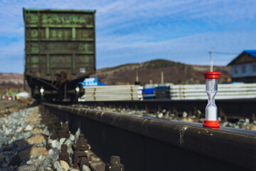 Railway freight cars on rails with hourglass, the concept of saving time on railway transportation.