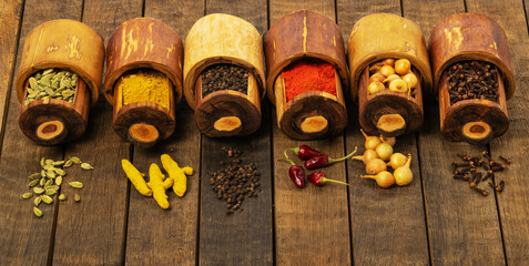 Various spices cinnamon, turmeric, pepper and anise, onions, coriander in wooden boxes on a wooden table