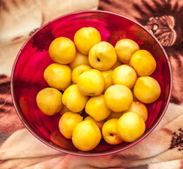 Yellow apples in a red plate close-up on a white-brown background