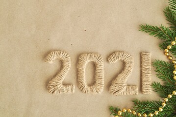 New year 2021 concept. Holiday background with numbers in 2021 on a brown Kraft paper background with fir branches and cones. Flatly