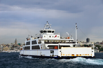 Naklejka premium Ferry goes to European side from Asian side of Istanbul under clear sky, full of vehicles. This is the alternative way for drivers instead of using bridges. Also Galata Tower is visible as background