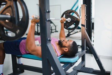 Weight lifter at the bench press lifting a barbell on an bench