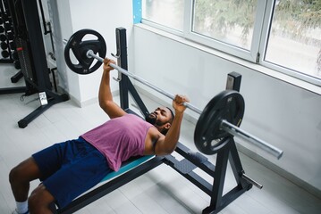 Weight lifter at the bench press lifting a barbell on an bench