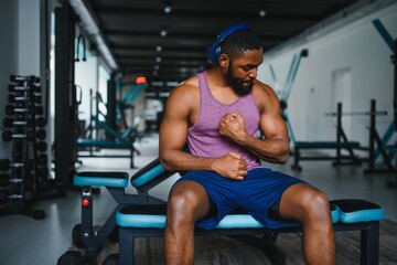 Black athlete flexing muscles, demonstrating strong biceps in gym.