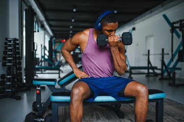 healthy african man working out with dumbbells in gym