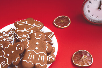Beautiful vintage silver alarm clock and plate of gingerbread cookies and slices of dried lemon on a bright red background