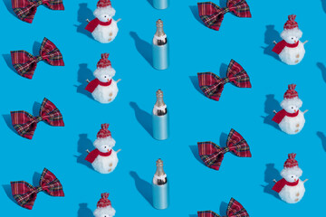 Christmas winter pattern made with bow tie, snowman and champagne bottle on blue background. Minimal New Year celebration festive concept. Flat lay, top view.