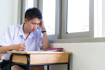 Concentration in exam in school of smart young asian student thinking serious in test final in...