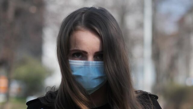 Sad Eyes Behind Face Mask of Young Woman Walking in City Outdoor During Covid-19 Virus Pandemic Looking At Camera, Slow Motion