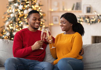 Millennial cheerful african american guy and woman clink glasses of champagne