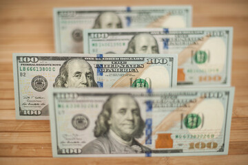 100 Dollars bill and portrait Benjamin Franklin on USA money banknote. Hundred dollar bills on wooden background..