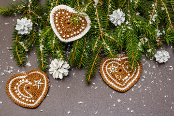 Border of Christmas tree branches and crocheted hearts on black stone concrete background