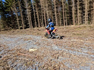 A little boy is enjoying his motocross ride in various poses on nature trails.