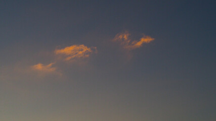 Ciel minimaliste, dans lequel ne circule que deux petits cumulus fractus, de couleur orangée
