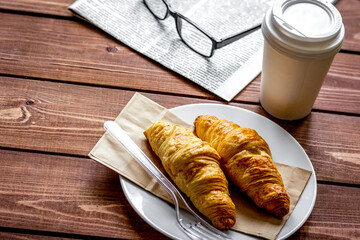 Business cup of coffee with croisant and newspaper on desk