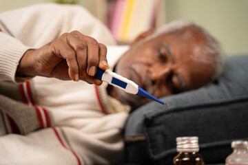 Obraz na płótnie Canvas Selective focus on thermometer, sick bed ridden old man seeing temperature on thermometer.