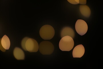 Background of golden, yellow bokeh (led strip light in a 50mm lens) on a dark black background.  Design elements