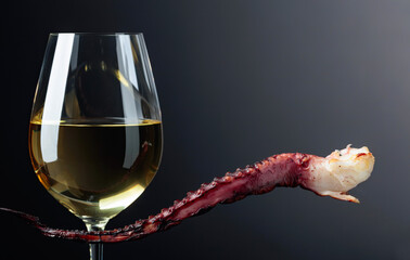 Grilled octopus and white wine glass on a black background.