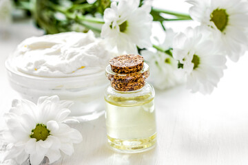 Fototapeta na wymiar homemade cosmetics with camomile herbs on white wooden background