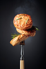 Delicious hot homemade cutlets with rosemary on a black background.