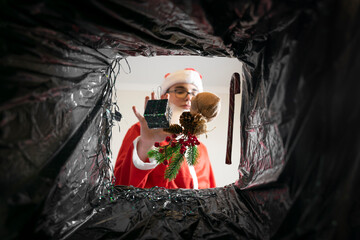 Santa throws gifts and Christmas decorations in the trash. view from the dumpster.