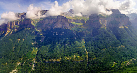Green landscape in the Pyrenees of the Ordesa and Monte Perdido valley with mountains, rocks, forests and sky with clouds. Top aerial view.
