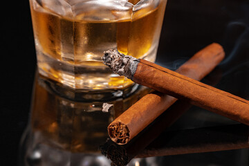 Glass of whisky and lighted cigar on black background