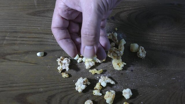 Hand picks up rock of crack cocaine drug from tabletop