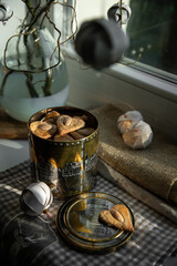 Metal box with homemade heart shaped  gingerbread cookies with almonds and Christmas ornaments on the windowsill. 