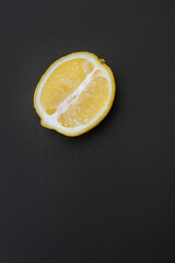 Half of a yellow ripe lemon lies on a black background, there is space for text. Background for a cooking blog about healthy eating.