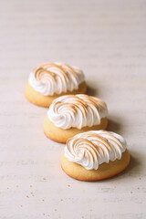 Butter Cookies with Lemon Curd and topped with Burnt Italian Meringue, on a light beige background.
