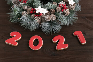 Christmas wreath and Inscription 2021 gingerbread cookie. Wooden background. Close up