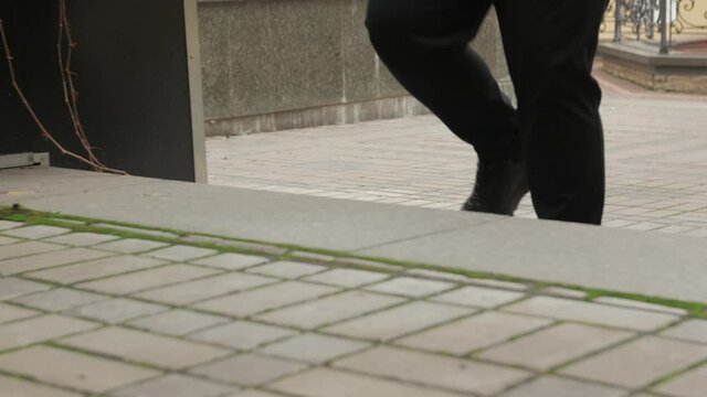 Unrecognizable man walking legs closeup outdoors black sneakers and pants tracking camera movement