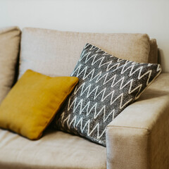 Close-up of pillows on cozy grey sofa. Soft cushions. Modern interior of living room.