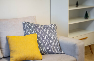 Contemporary interior of living room. Close-up of cozy sofa with soft cushions. White shelf.